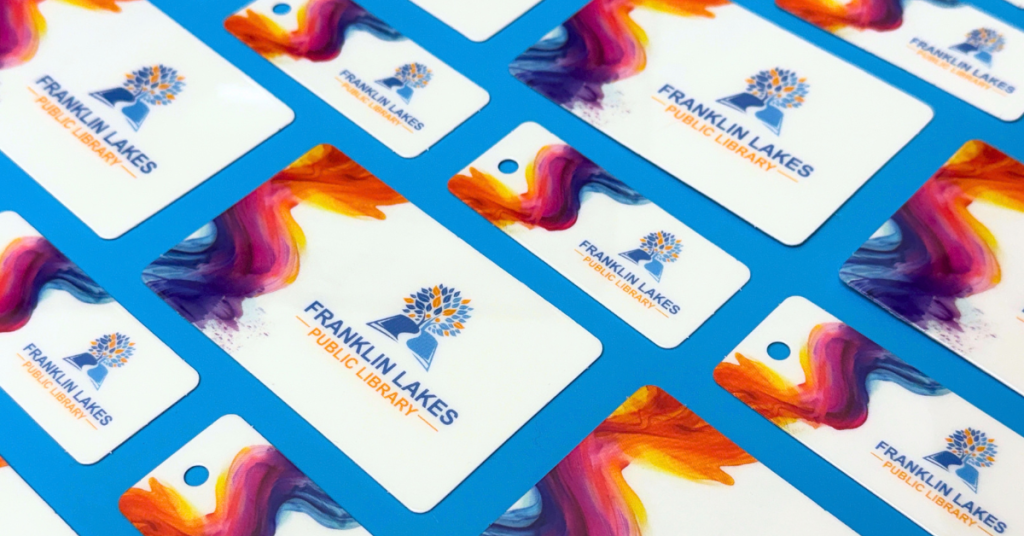 Franklin Lakes Public Library cards and key tags featuring a colorful abstract design, arranged on a bright blue background.